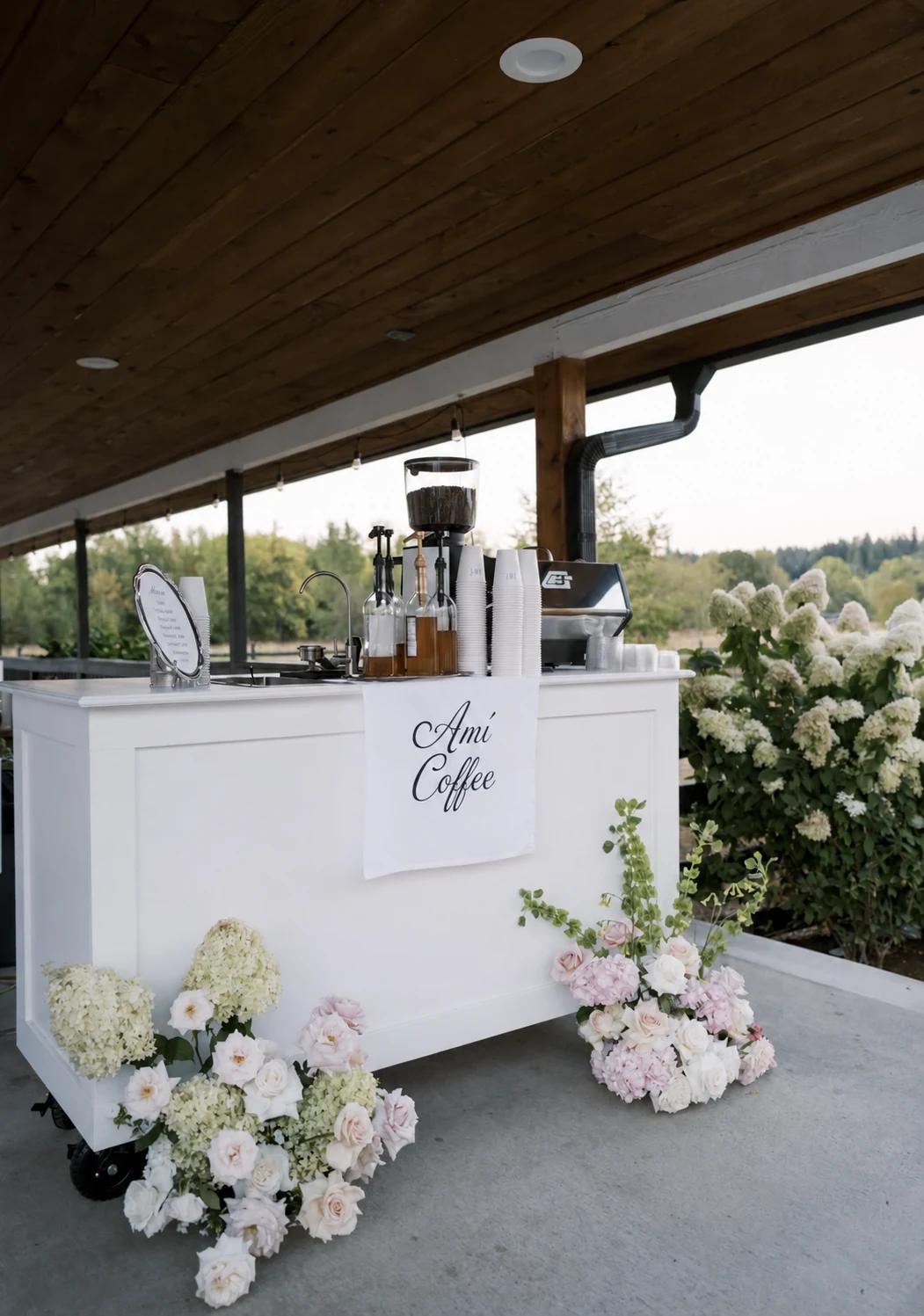 Our white AMÍ mobile coffee cart with espresso equipment, silver menu platter and wedding flowers